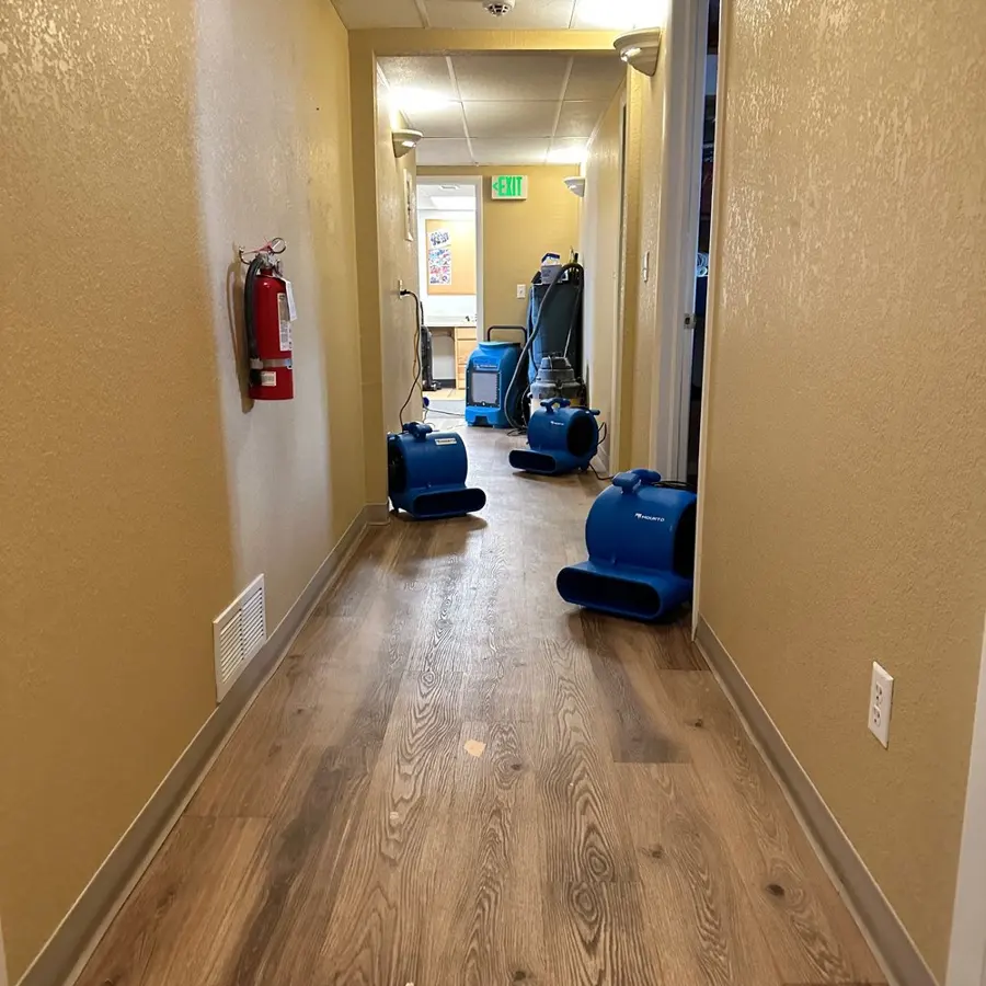 Air movers drying a wet hallway floor in a Greeley building