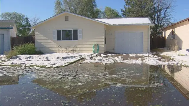 Hail piled in front of a Greeley area ranch home with storm water standing in the yard