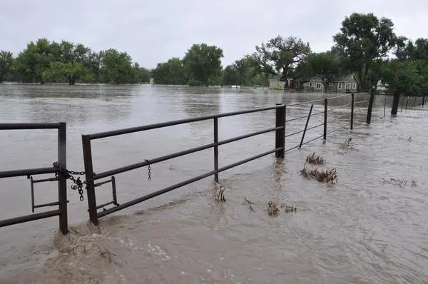 Floodwater running over a fence line near homes in Weld County